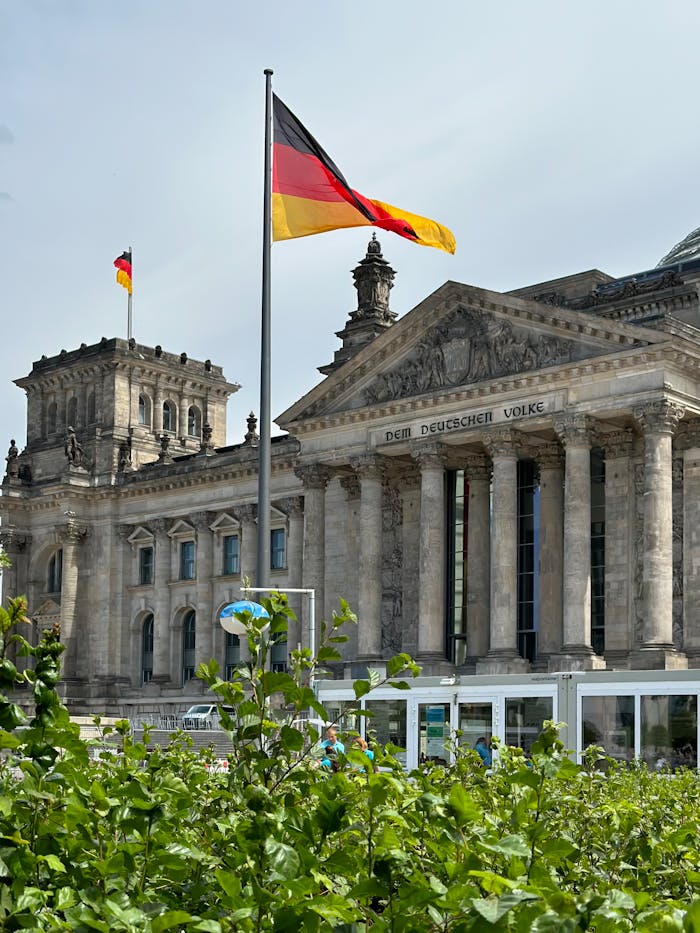 Historic Reichstag building and German flags in Berlin, symbolizing German government and architecture.
