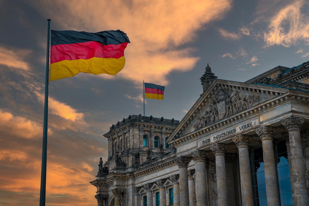 Iconic Reichstag building in Berlin, Germany with national flags at sunset, showcasing architectural beauty.