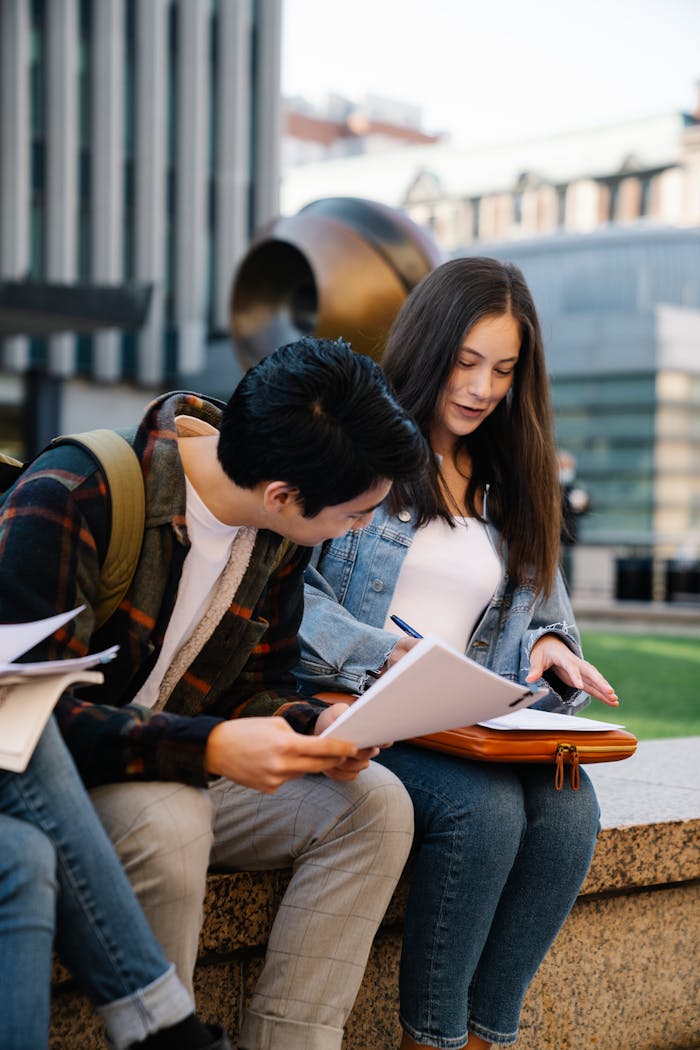Two college students studying and discussing notes outside on campus.